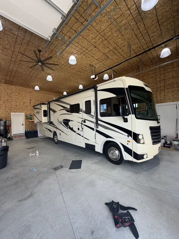 Class A motorhome pulled into a shop bay with tools laid out